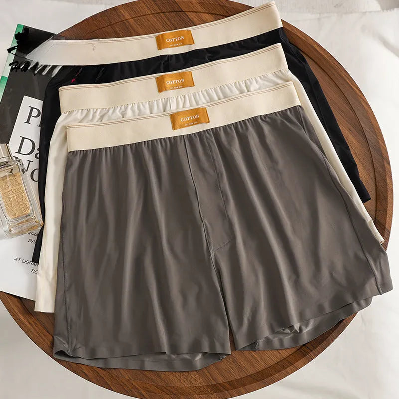 Pack of three men's solid colour loose fit ice silk underwear briefs on a grey background.