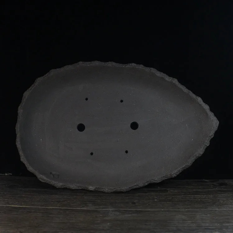 Handmade purple clay flower pot showing unique shape and traditional ceramic texture