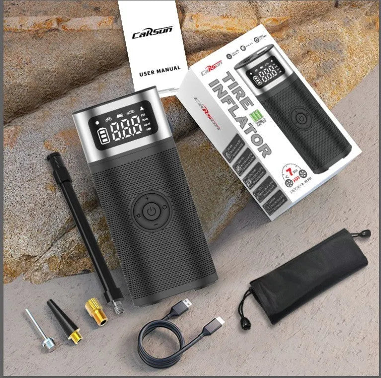 Black portable wireless smart air pump with display, charging cable and nozzle attachments on a dark surface.