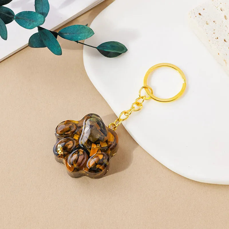 Natural crystal cat's paw shaped keychain charm on a keyring, showing colour variations of different gemstones.