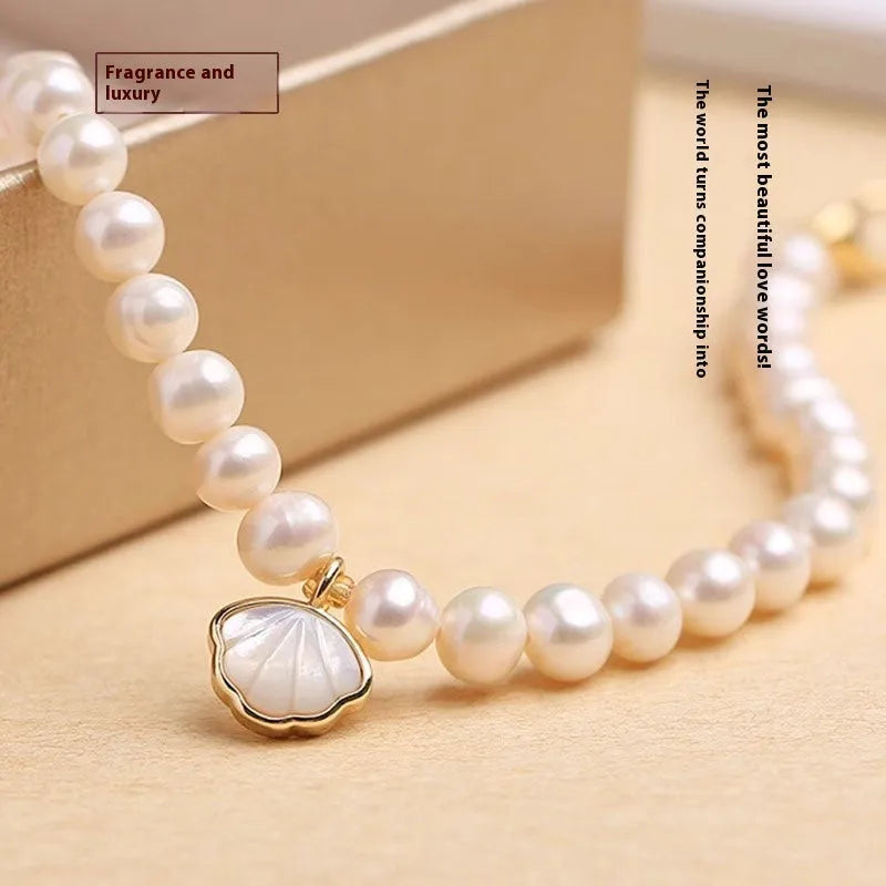 Freshwater pearl bracelet with fan-shaped shell setting and elastic string or extension chain fastening.