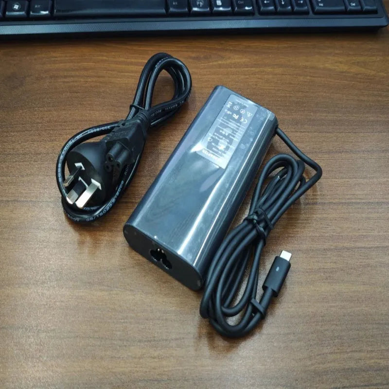 Black oval 65W USB-C laptop power adapter with Type-C port and multiple international power cords