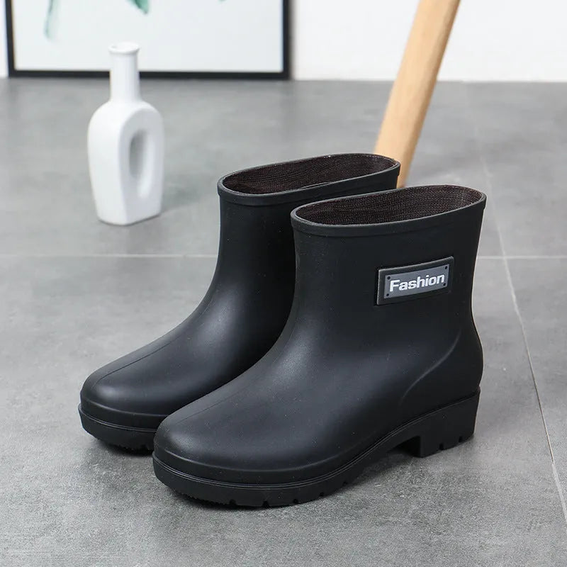 Women's mid-calf PVC rain boot in black with a low heel on a white background.