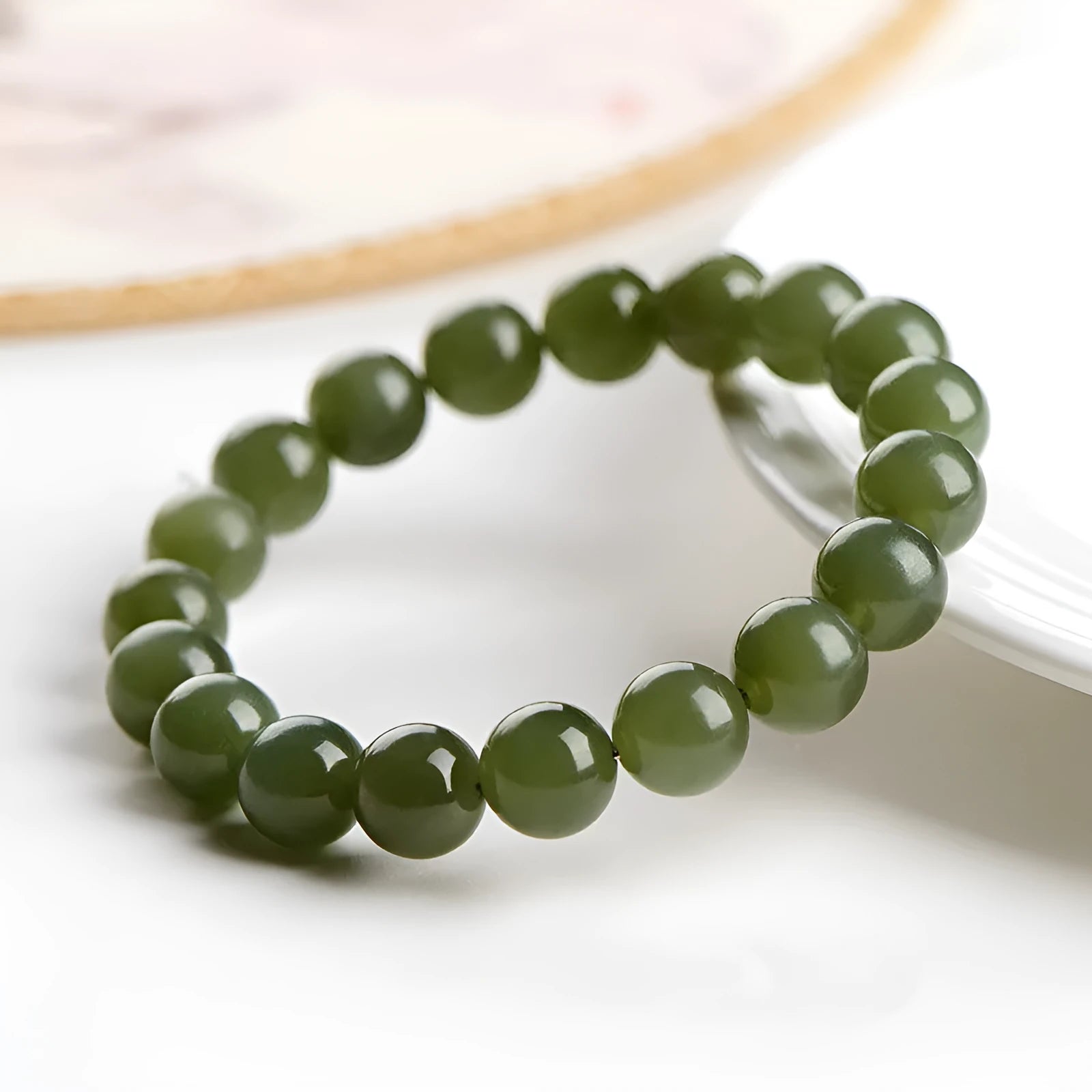 A close-up of a Hetian jade ball bracelet showing polished spherical beads in a clear stone colour, laid flat.