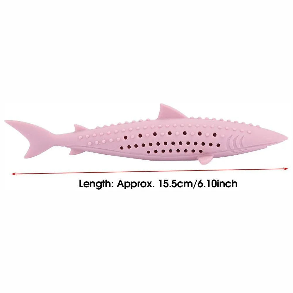 Green silicone fish-shaped cat chew toy with breathable side holes on wooden floor