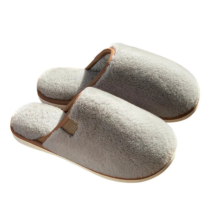A pair of solid colour plush winter slippers with a non-slip PVC sole and car stitching detail.