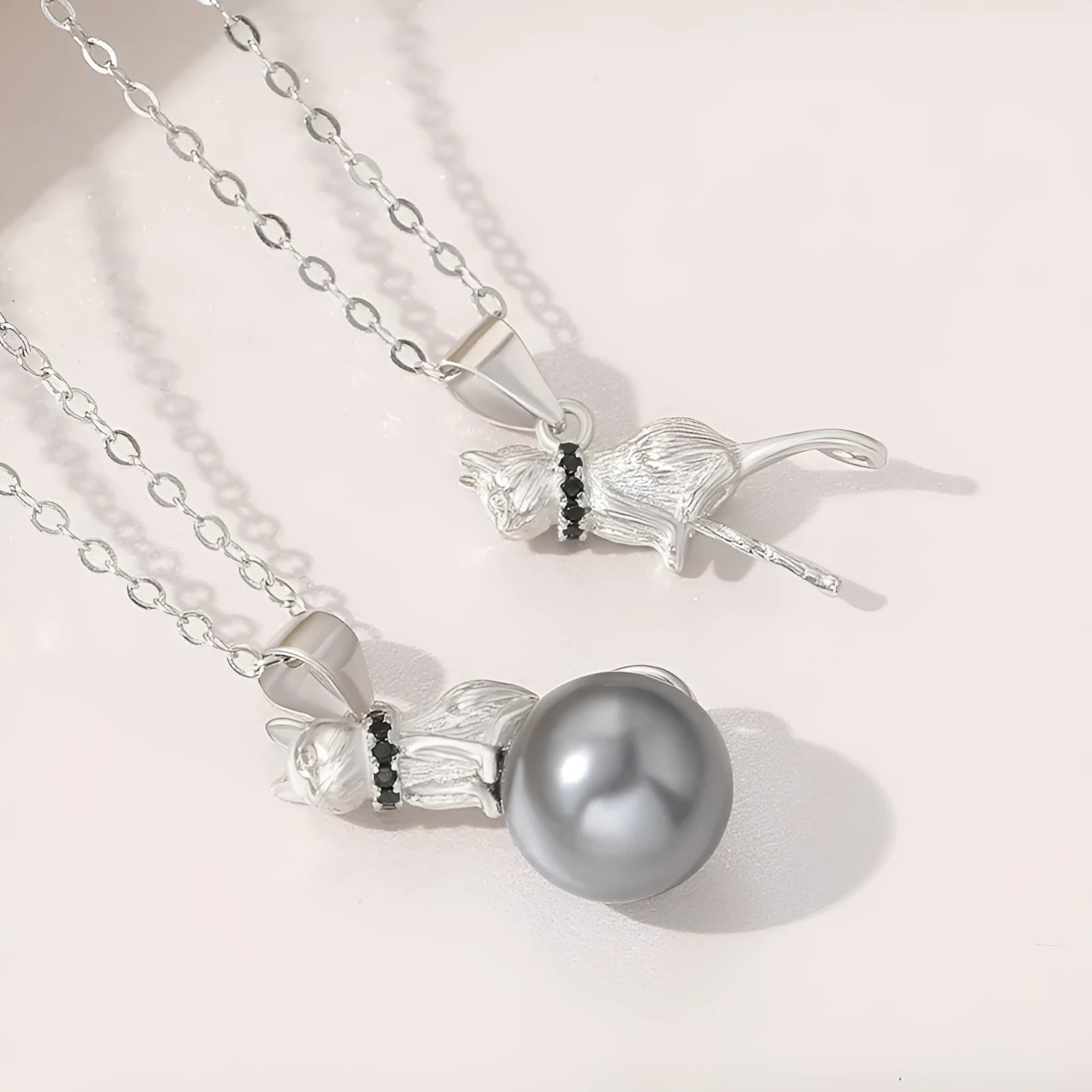 Close-up of a sterling silver cat silhouette pendant on a delicate silver chain.