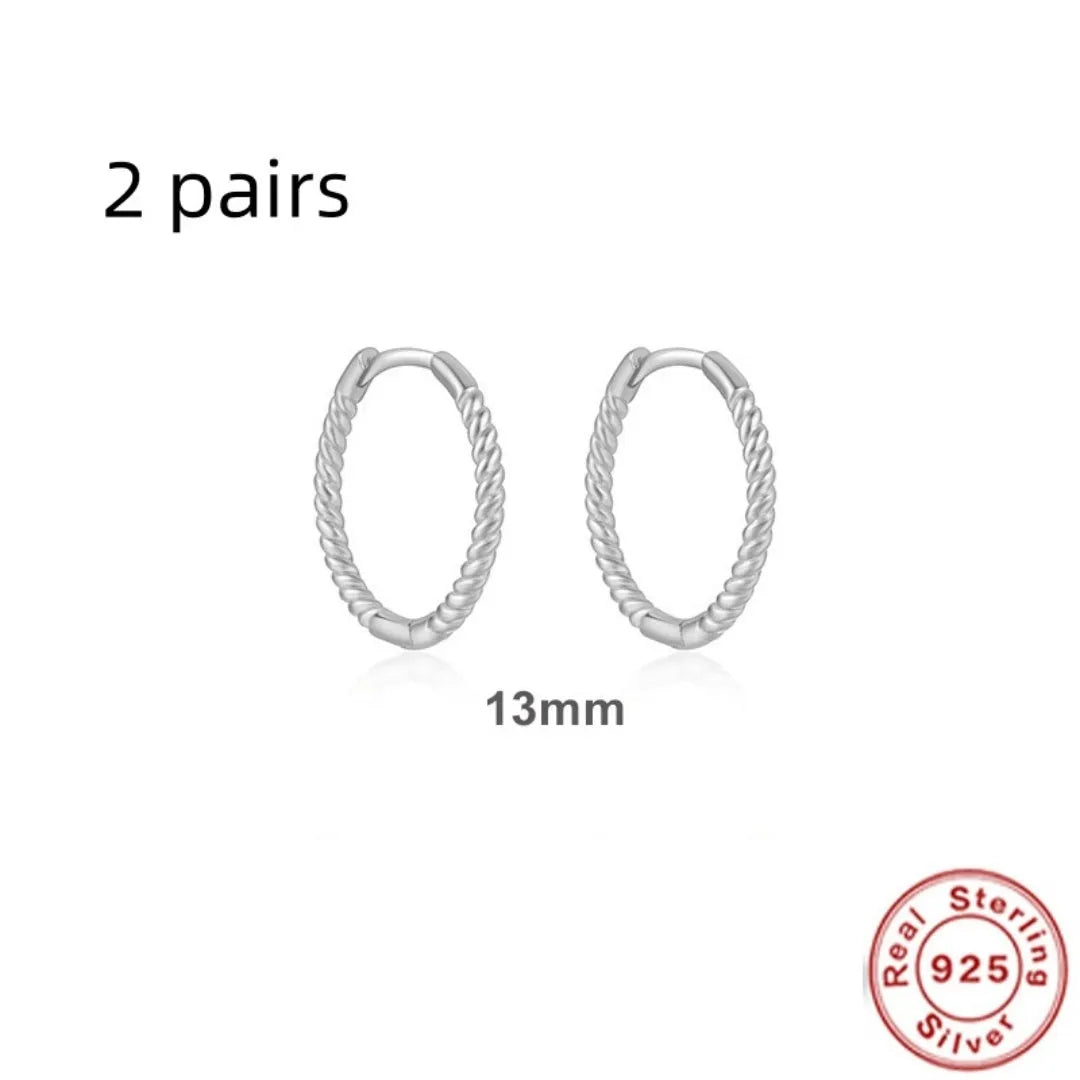 A pair of twisted sterling silver round earrings in a geometric design on a white background.