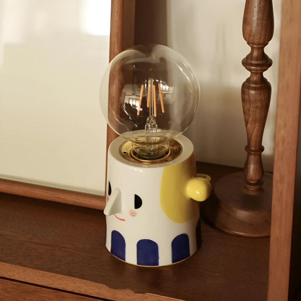 Handmade ceramic bedside lamp with a ball headlight design on a table.