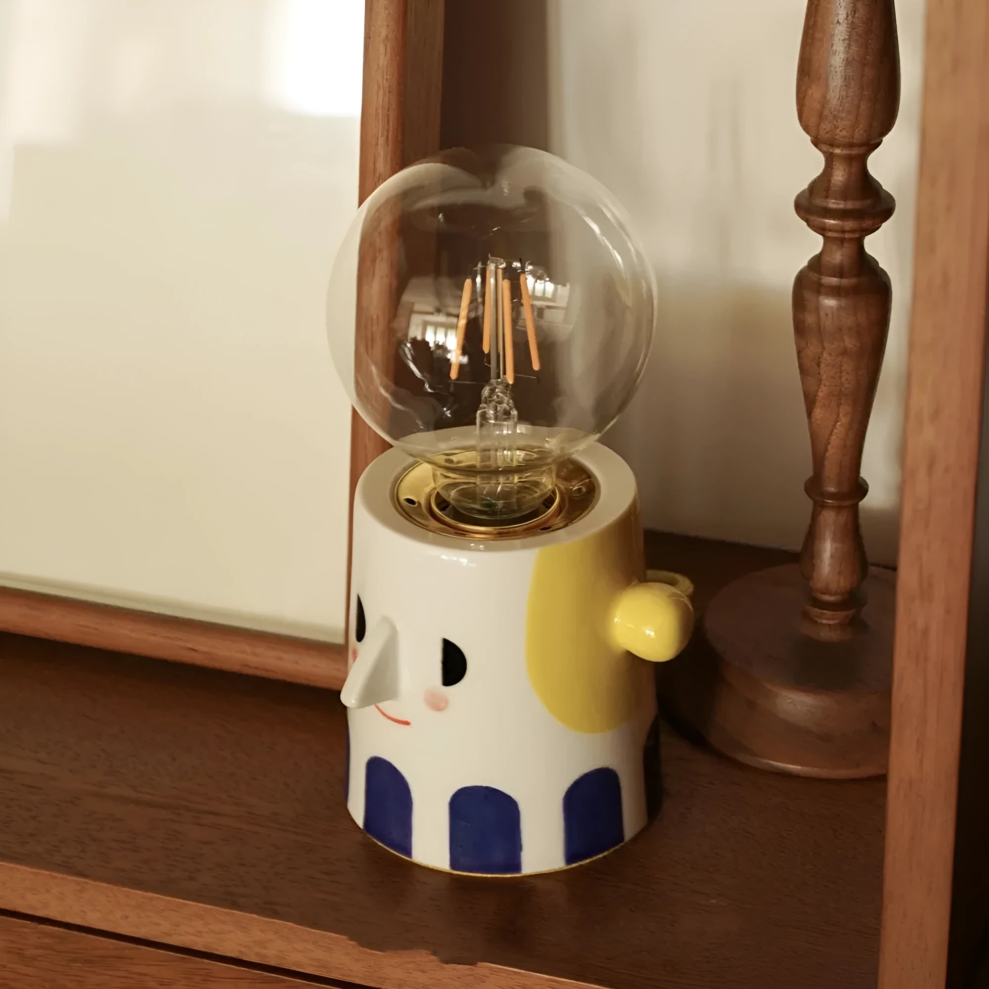 Handmade ceramic bedside lamp with a ball headlight design on a table.