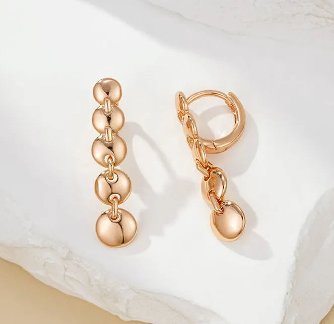 A pair of long gold-colour retro earrings with a woven round circle design made from copper.