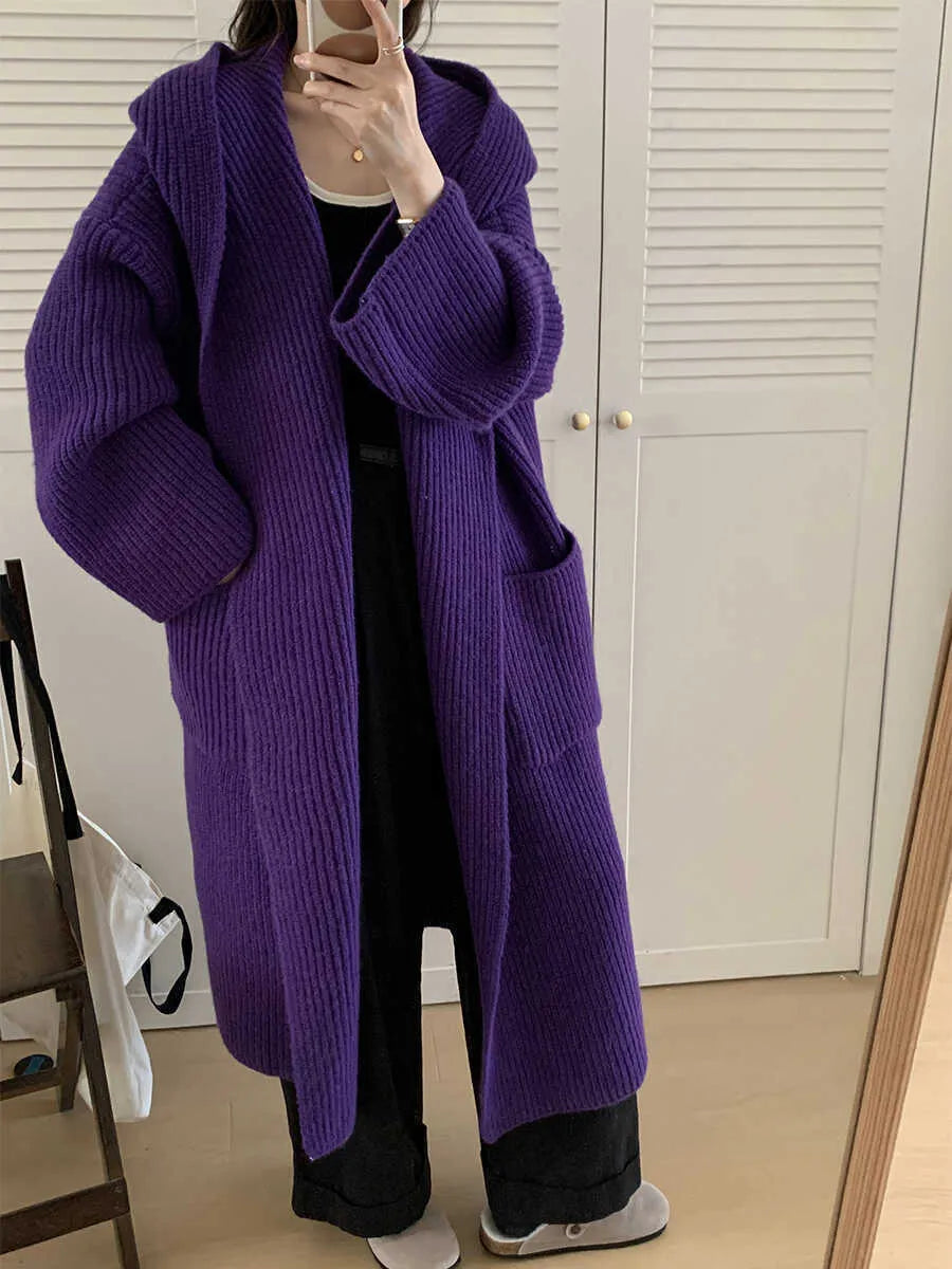 A long, loose grey hooded cardigan coat for women on a hanger, showing its length and raglan sleeves.