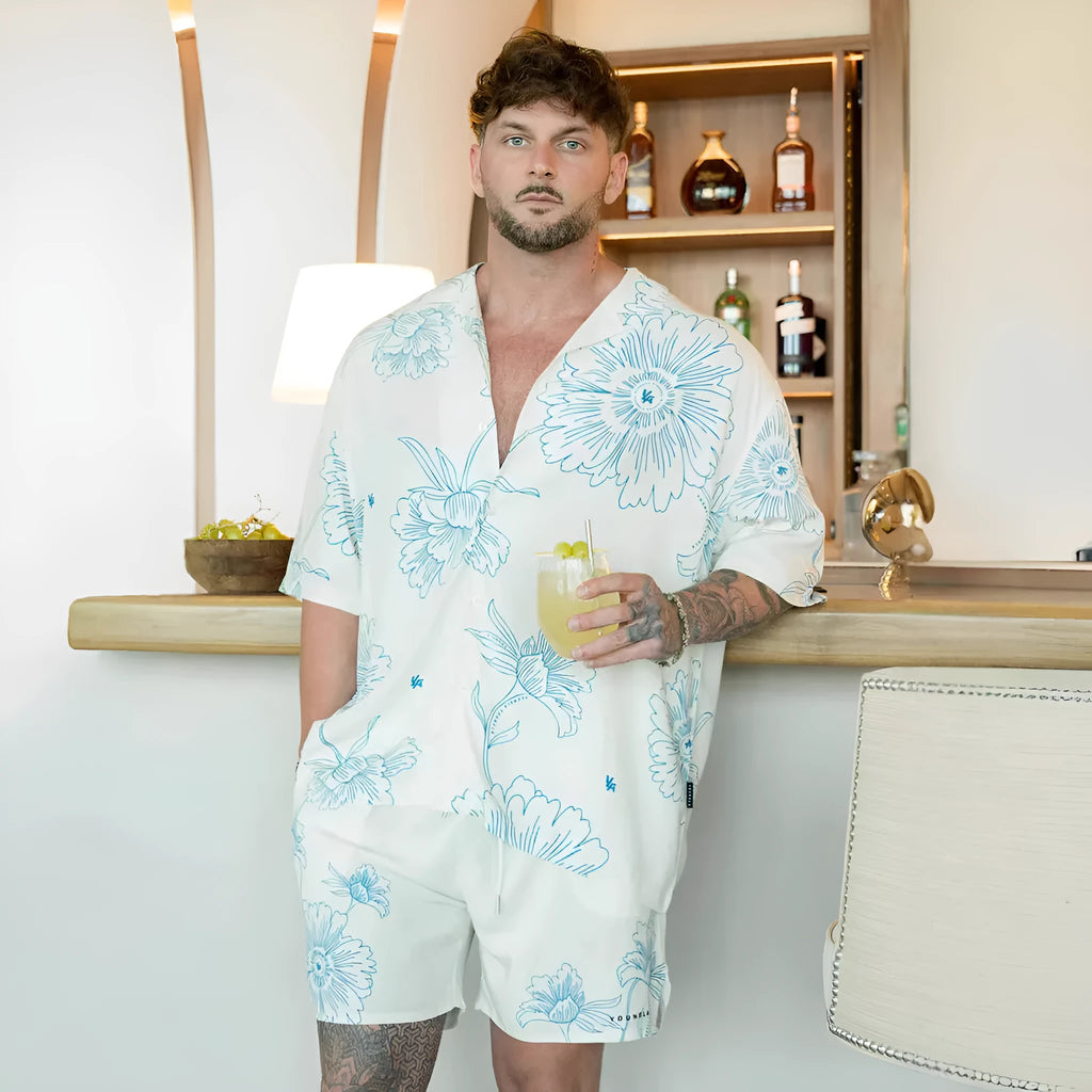 A man's loose-fitting, short-sleeve casual top with a floral print, shown in a light colour.