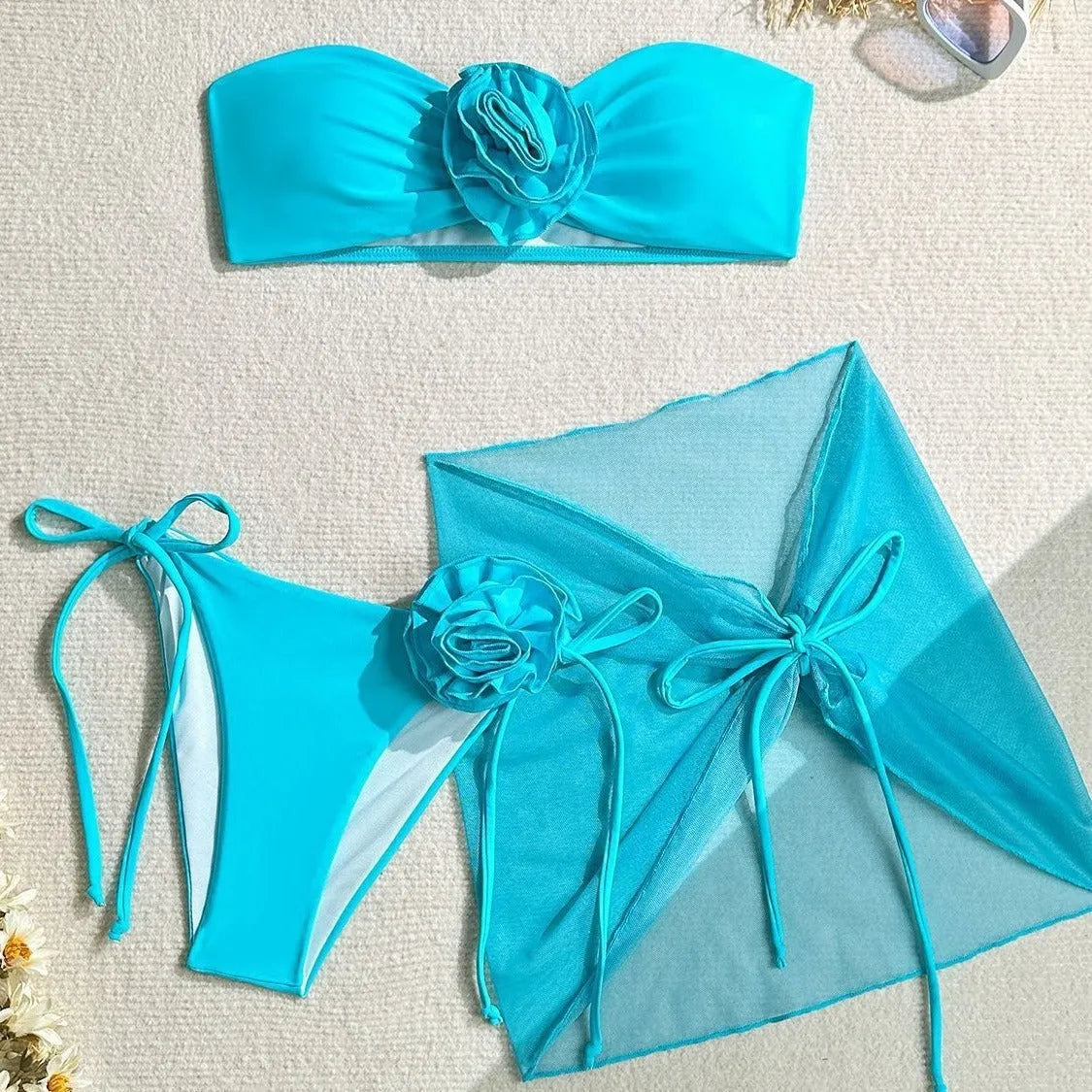 Women's pink tube top bikini with large 3D flower, matching bottoms, and skirt laid flat.
