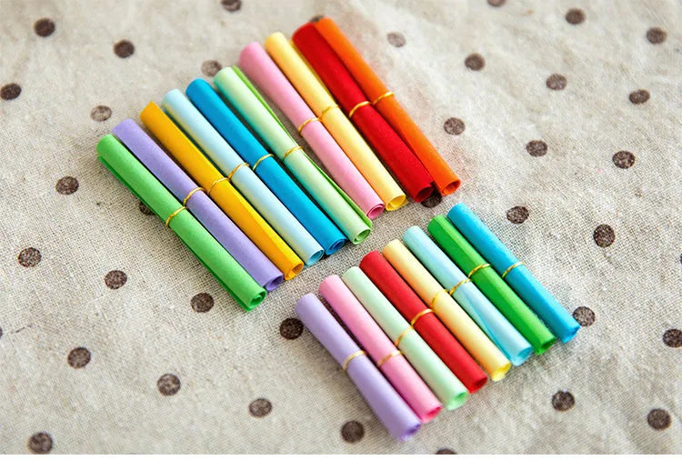 Assorted colourful paper scrolls with metal eyelets for messages and craft projects.