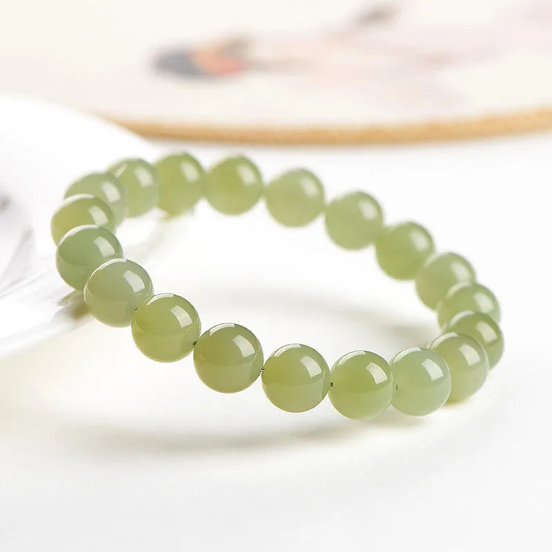 A close-up of a Hetian jade ball bracelet showing polished spherical beads in a clear stone colour, laid flat.