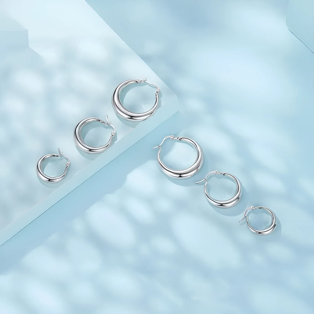 A pair of copper ring-shaped ear clip earrings with silver posts on a white background.