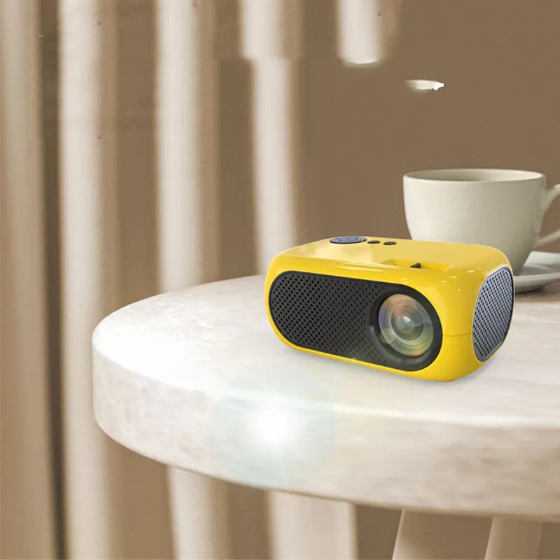 M24 Micro Mini LED Projector in Gold or White colour with power adapter and cables on a table.