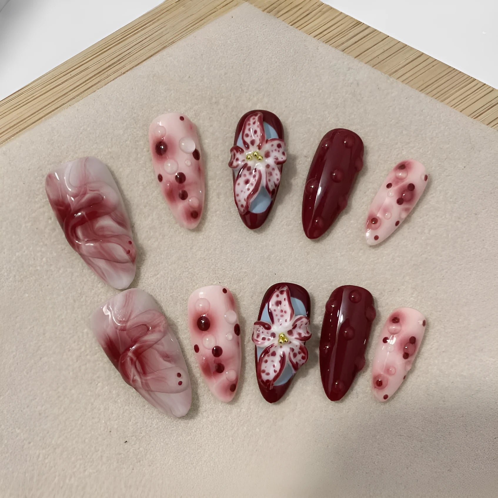 Hand-painted three-dimensional carved almond colour wear nails showing rose pattern in medium length
