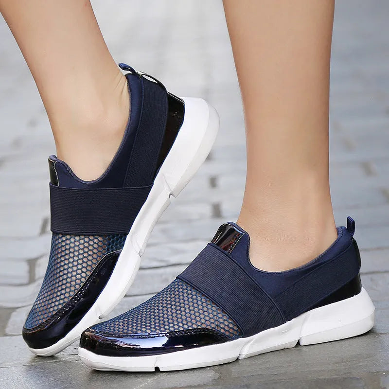 Women's blue, black, and grey lightweight mesh low-top sneakers on a hard floor.