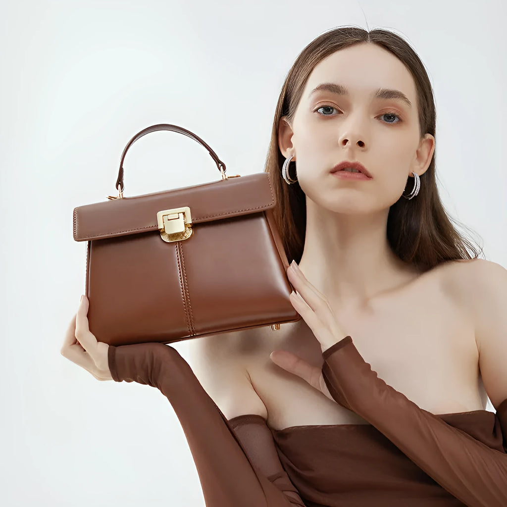 Women's black genuine leather shoulder bag with gold clasp closure showing interior compartments