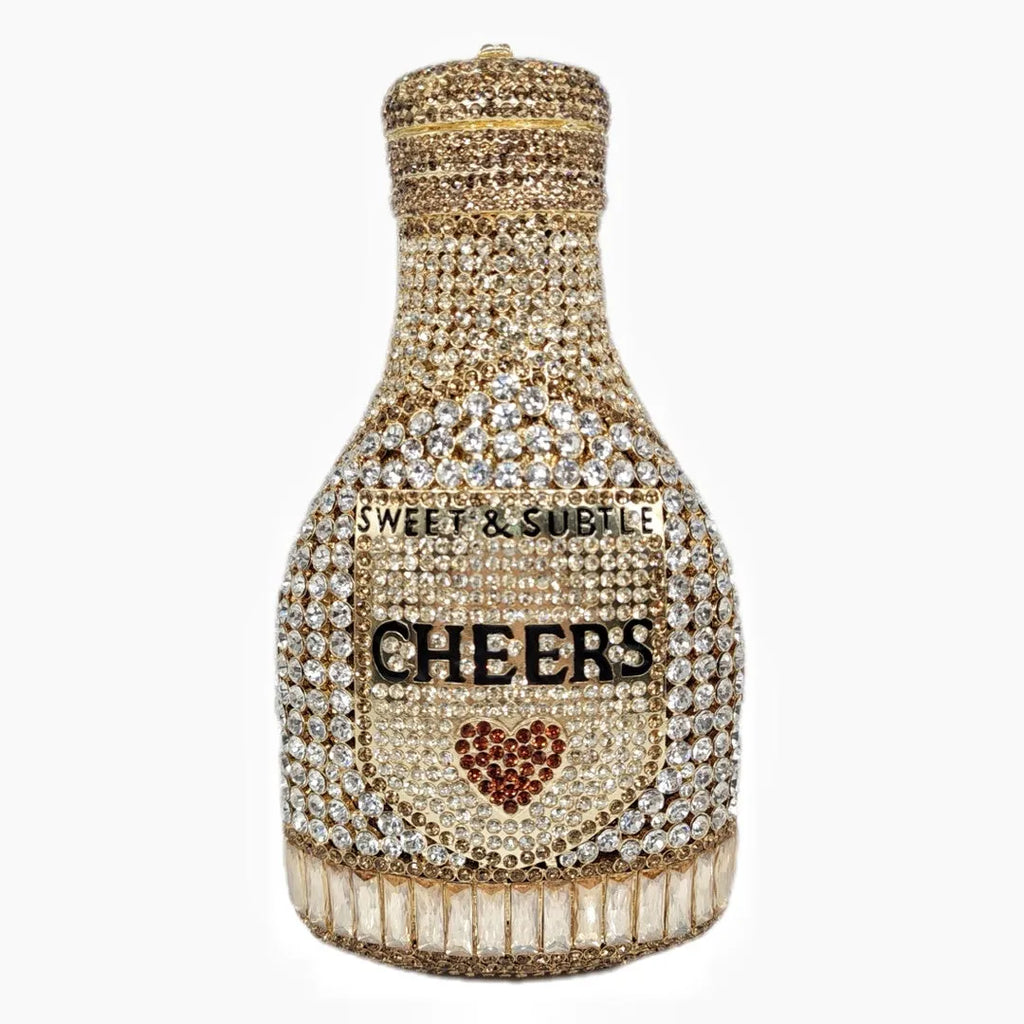Gold rhinestone champagne bottle shaped evening clutch bag with wrist strap on a dark background.