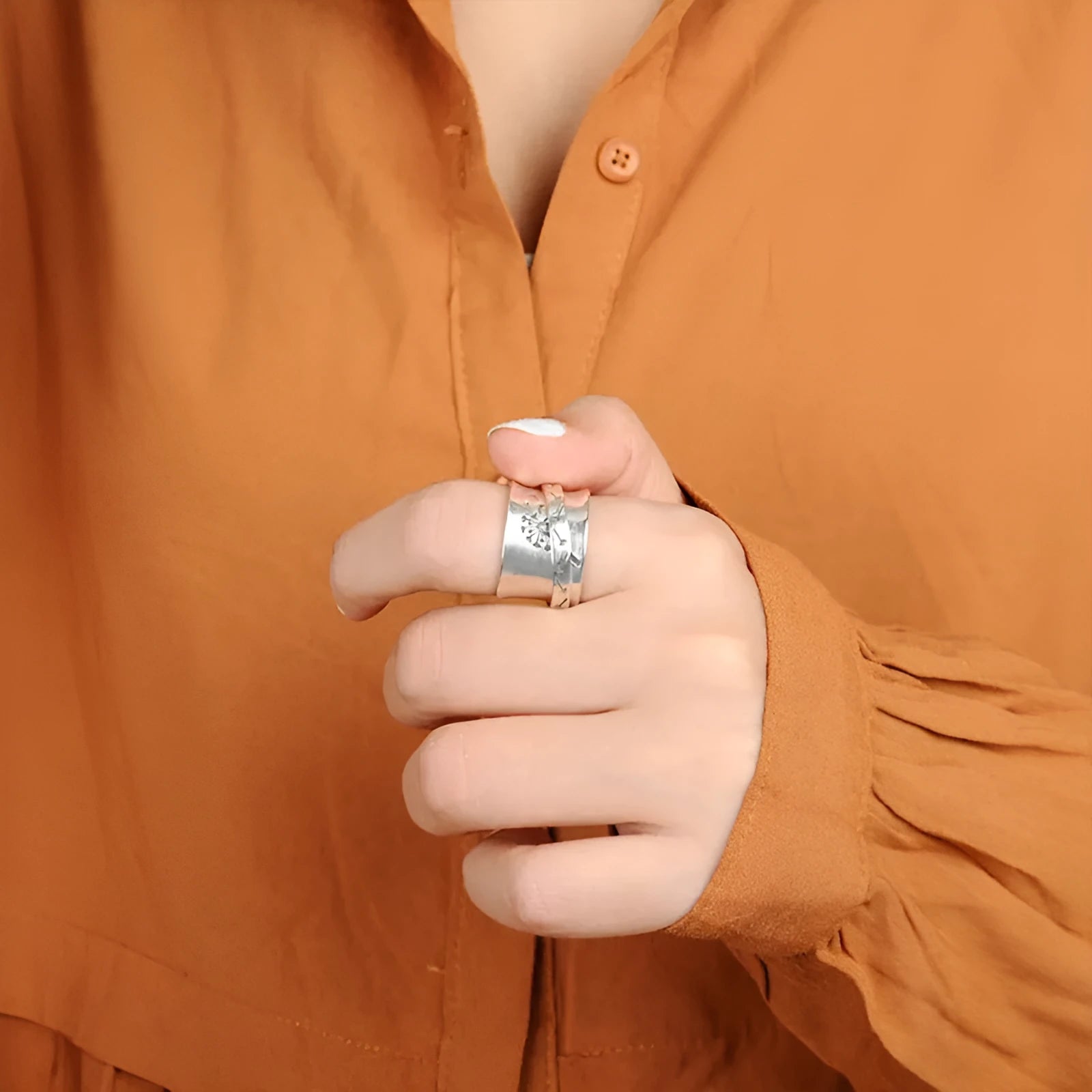 Silver electroplated alloy flower ring with rotating element on a hand.