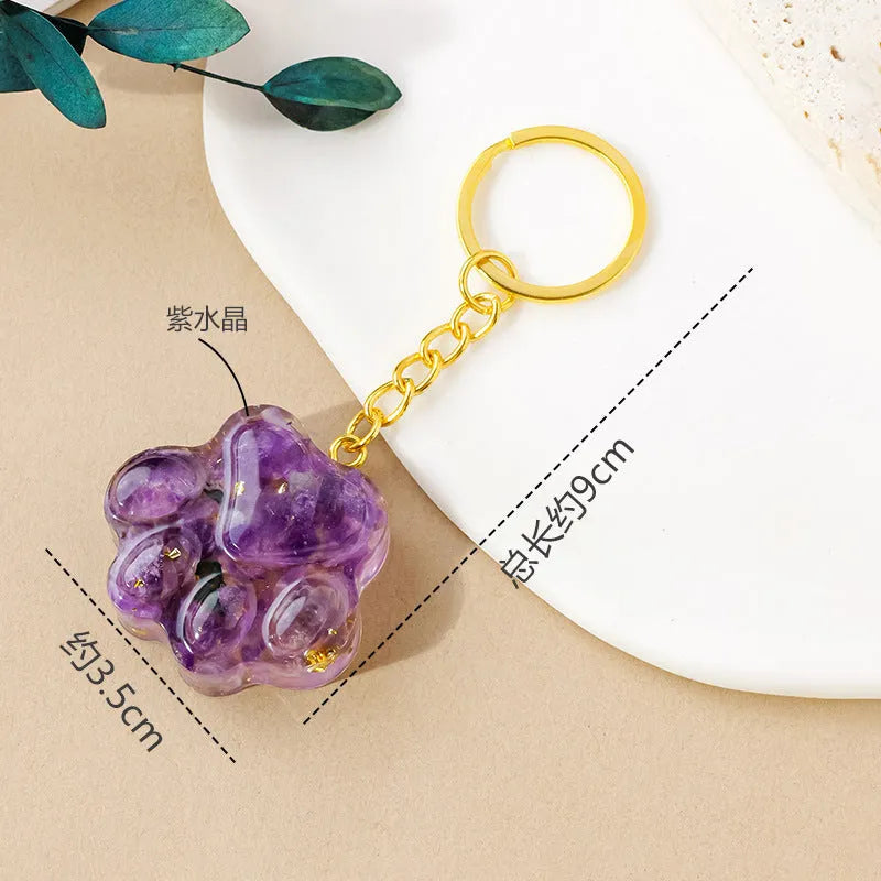 Natural crystal cat's paw shaped keychain charm on a keyring, showing colour variations of different gemstones.