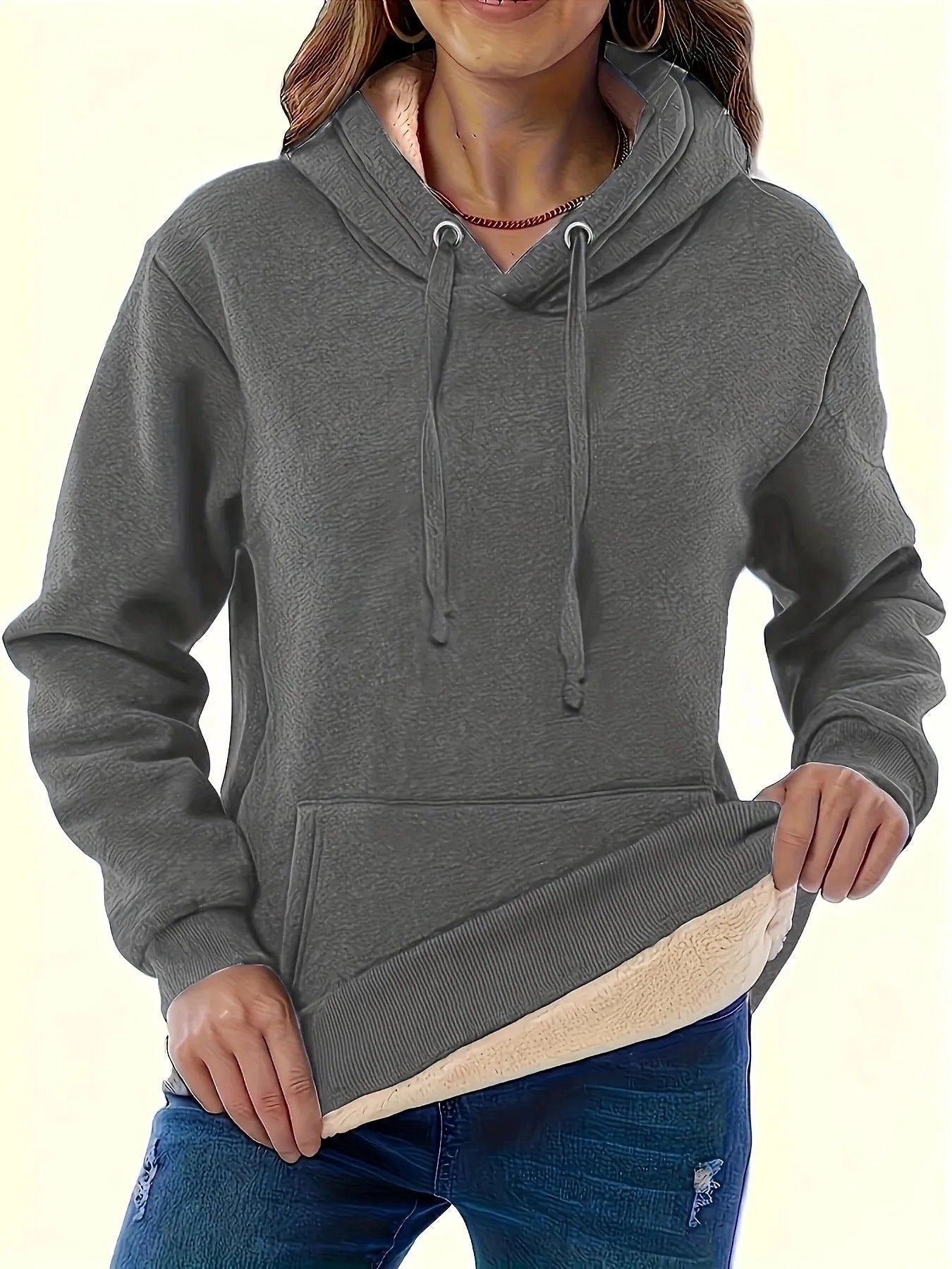A women's loose fit hooded sweater in thick grey polyester with side pockets and long sleeves.
