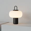Minimalist Nordic glass bedside table lamp with warm light on wooden surface