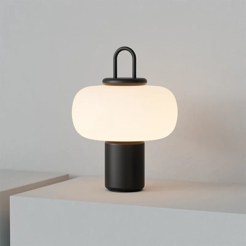 Minimalist Nordic glass bedside table lamp with warm light on wooden surface
