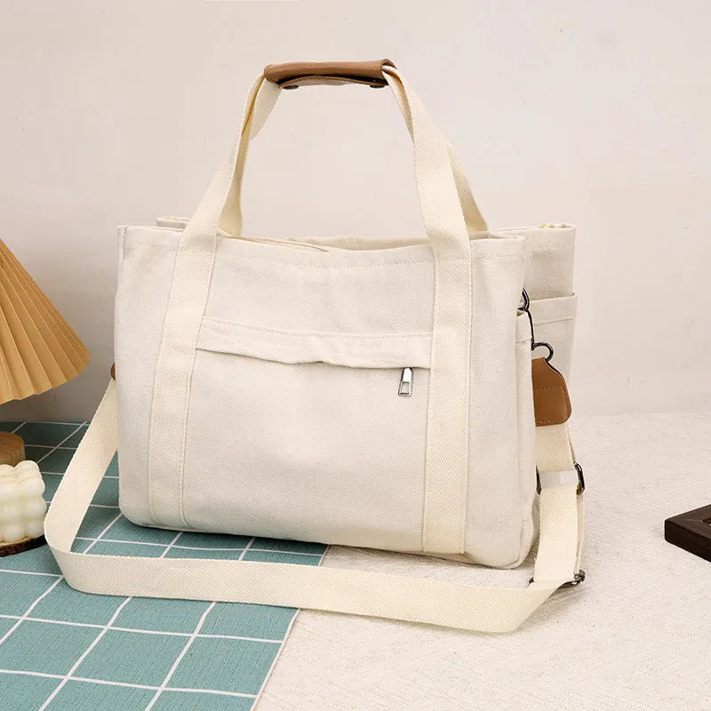 Large khaki canvas tote bag for women with open top showing internal laptop and camera pockets