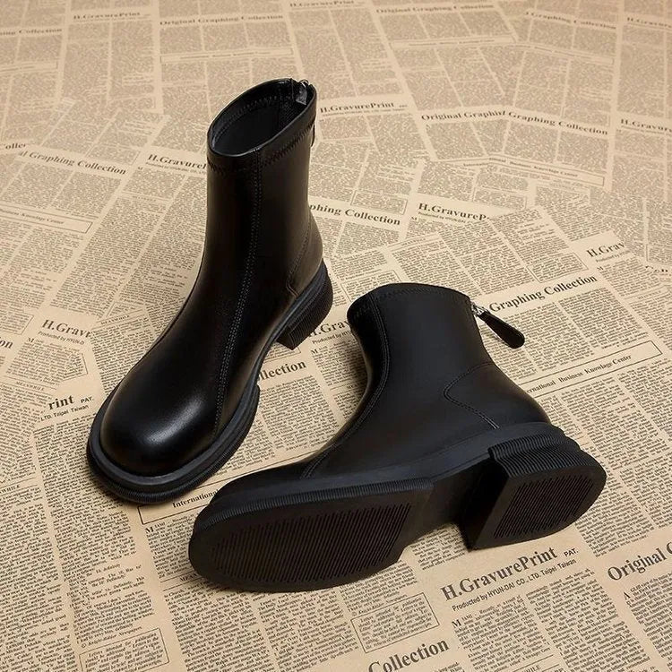 Women's black flat-heel ankle boot with back zipper and round toe on a neutral background.