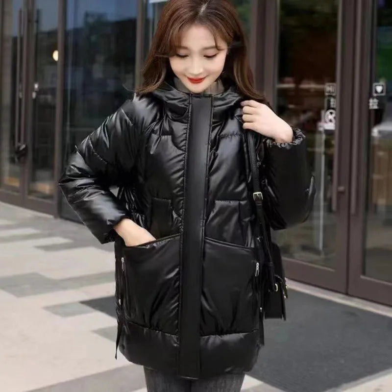 A green loose-fit hooded winter jacket for women on a hanger, showing long sleeves and thick insulation.