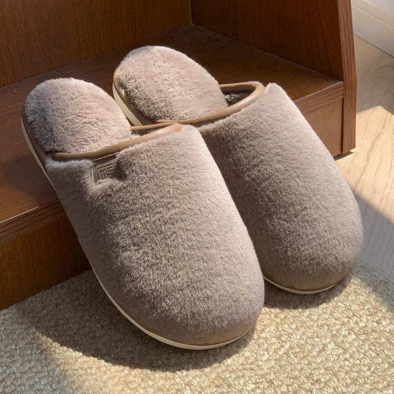 A pair of solid colour plush winter slippers with a non-slip PVC sole and car stitching detail.