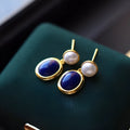 A pair of simple silver earrings with blue lapis lazuli pearls and auspicious patterns.