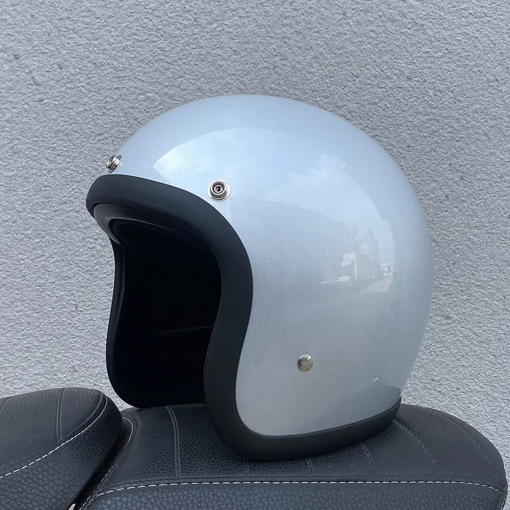 A cement grey retro-style motorcycle half helmet with a floral pattern on the side, showing its open-face design.
