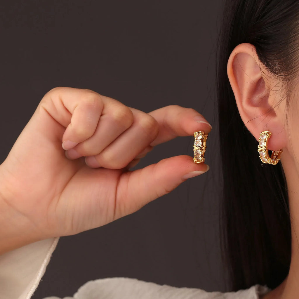 A pair of geometric clover cross earrings with a hexagonal shape in a silver or gold electroplated finish.