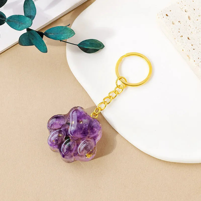 Natural crystal cat's paw shaped keychain charm on a keyring, showing colour variations of different gemstones.