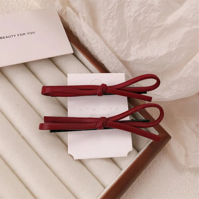 Close-up of a wine red leather bow barrette hair clip on dark hair.