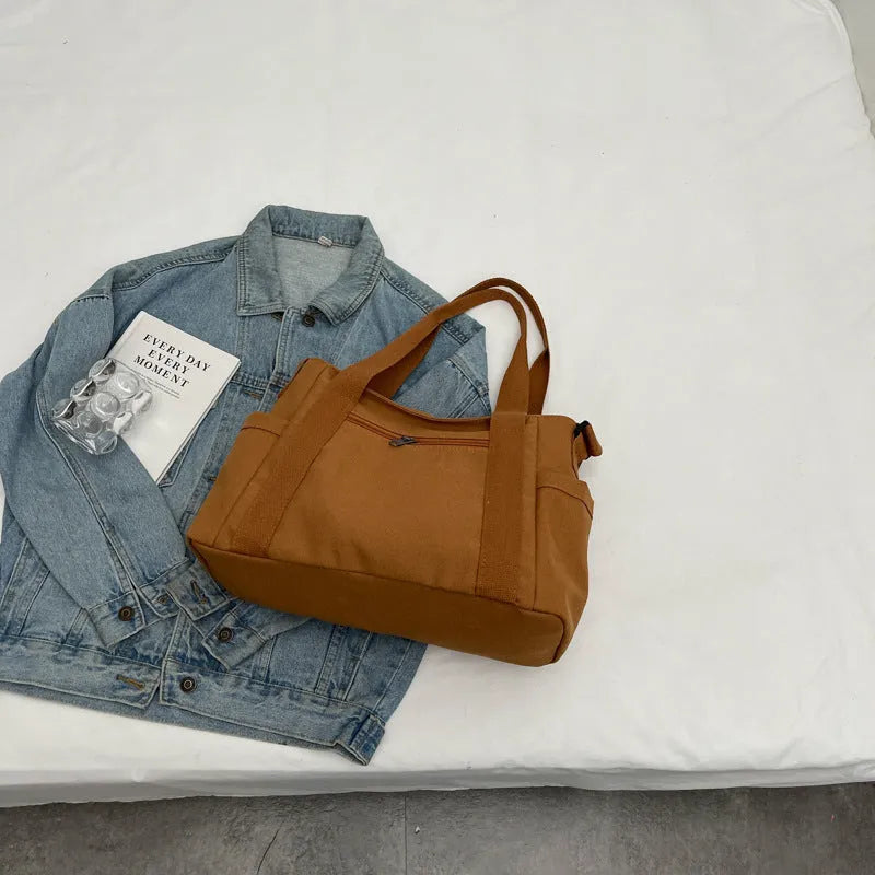 Large black polyester canvas shoulder tote bag showing outer sandwich pocket.