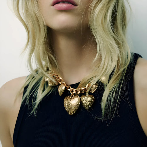 Carved heart-shaped alloy pendant on a metal chain necklace in gold colour.