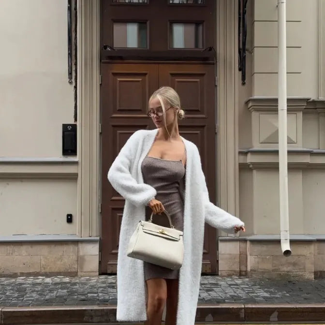 White long knitted cardigan jacket with regular sleeves on a hanger.