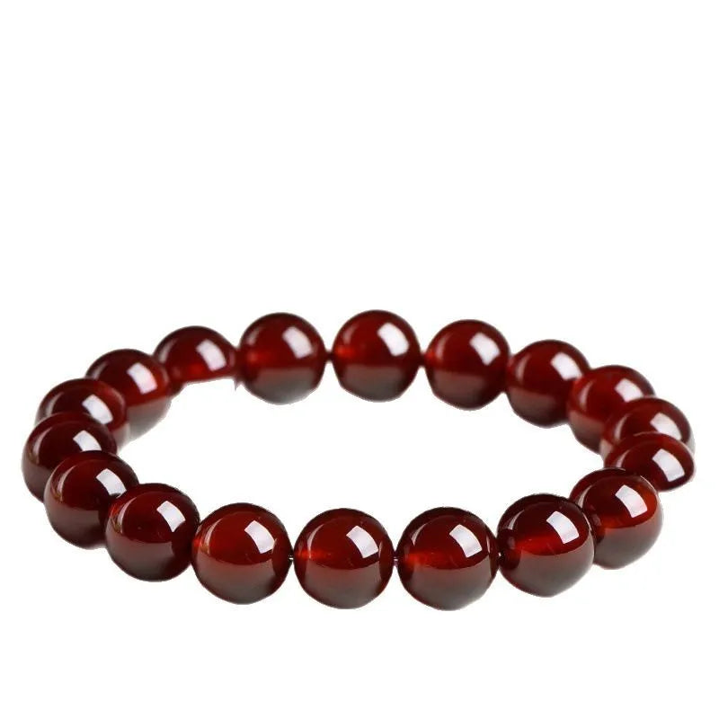 Natural orange red garnet crystal bead bracelet with a ruyi charm on a wrist.