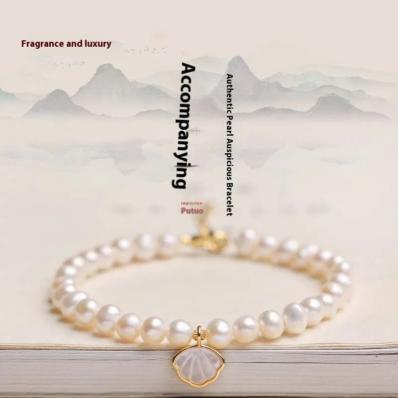 Freshwater pearl bracelet with fan-shaped shell setting and elastic string or extension chain fastening.