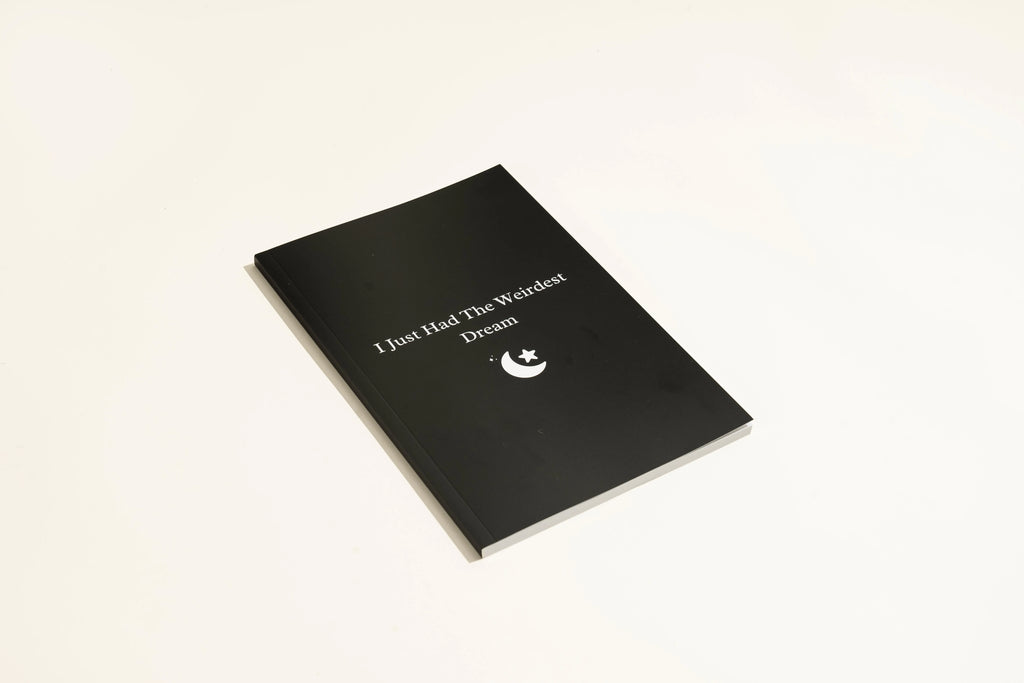Black softcover Dream Journal notebook open on a table