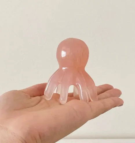 Small pink octopus-shaped natural resin massage comb with storage bag.