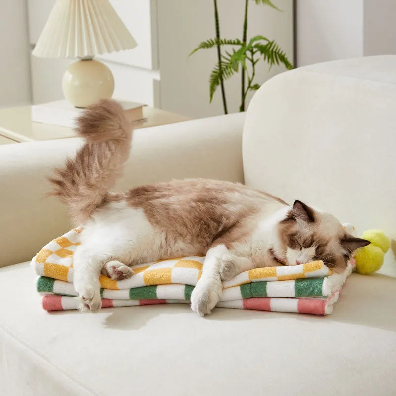 Plush pet blanket with plaid pattern and decorative fur ball in green colour