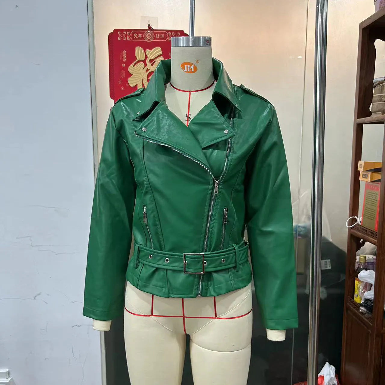 Black punk style short leather jacket with a Peter Pan collar and drawstring waist on a hanger.