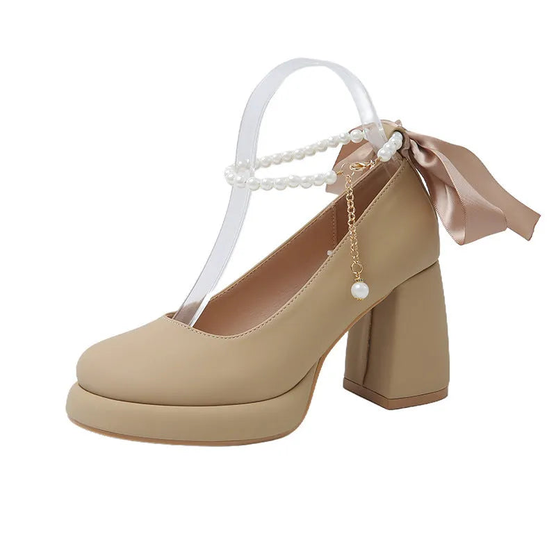 Women's beige Mary Jane shoes with a chunky heel and an ankle-strap buckle on a round toe.